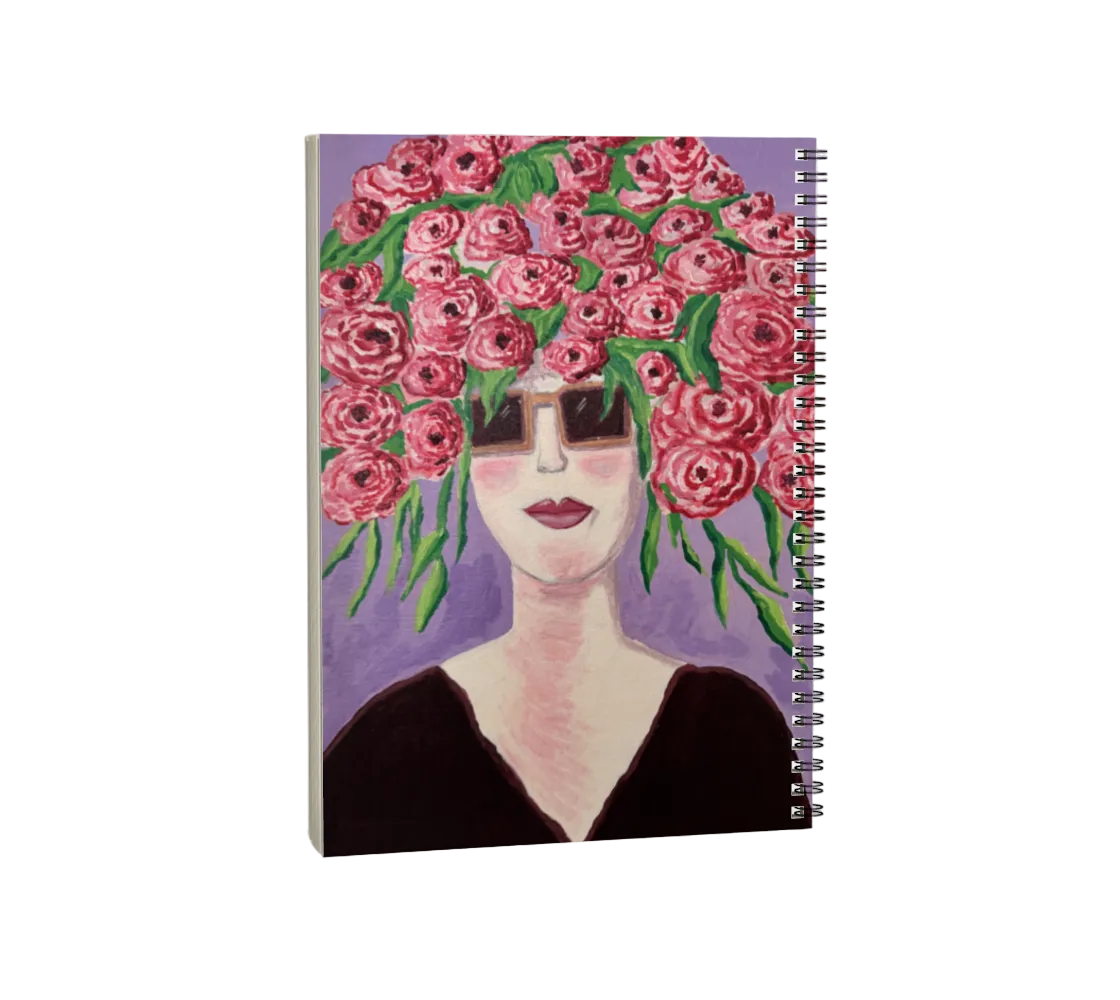 Notebook with a design of a woman's face with pink flowers on her head against a purple background