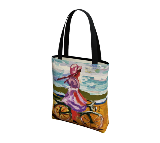 A canvas tote bag with black handles, featuring a colorful artistic print of a woman riding a bicycle by the sea. The print has a textured, impressionistic style with blue, pink, orange, and green tones.