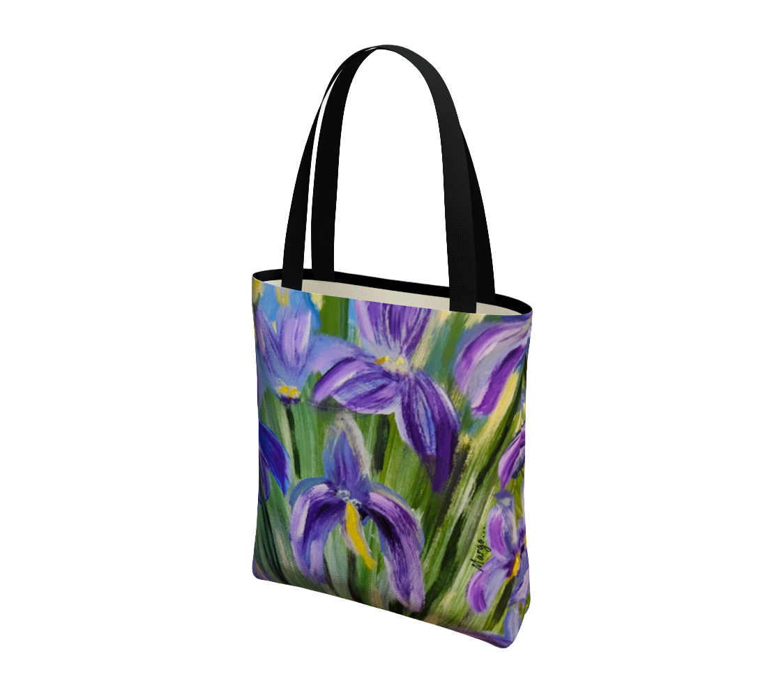A canvas tote bag featuring a painted floral design of purple irises on a green background, with black shoulder straps, shown on a plain white background.